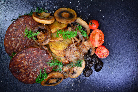 Meatloaf with mushrooms, onions and tomatoes on a black background