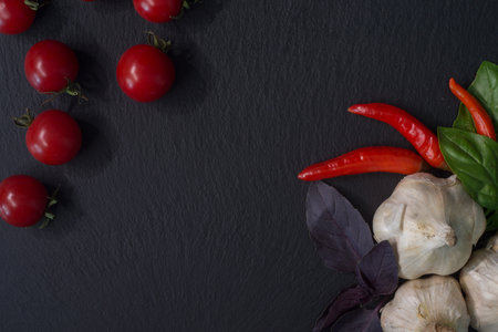 Fresh vegetables and spices on black slate background. Top view with copy space