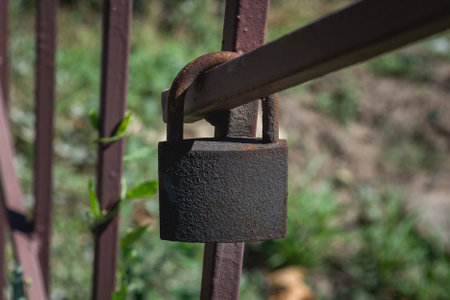 Old padlock on a steel fence in the garden. Selective focus.の写真素材