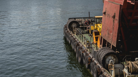 Tugboat unloading bulk cargo of iron ore at a port