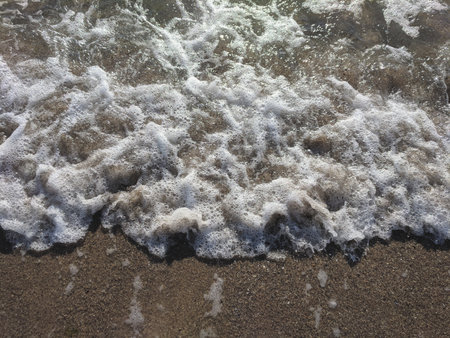 Waves of the sea breaking on the sandy beach with sand.