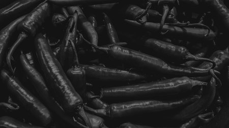 Black hot chili peppers on a black background. Black and white photo.の写真素材