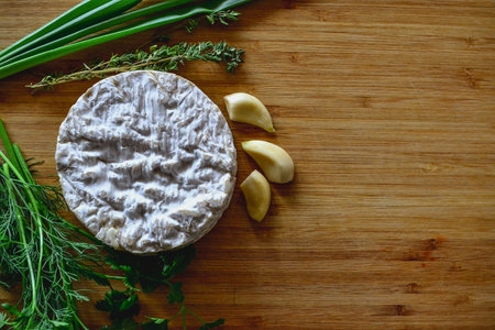 Camembert cheese with garlic and herbs on a wooden cutting boardの写真素材