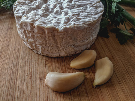Camembert cheese with garlic and parsley on a cutting boardの写真素材