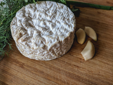 Camembert cheese with garlic and dill on a wooden boardの写真素材