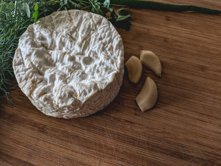 Camembert cheese, garlic and herbs on a wooden cutting boardの写真素材