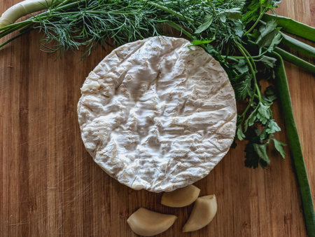 Cheese on a cutting board with parsley and dillの写真素材