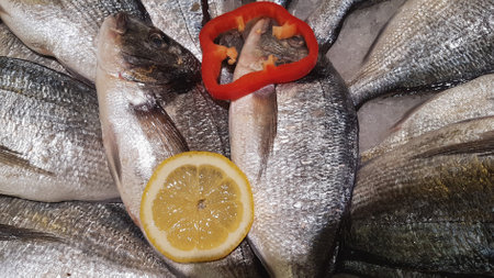 Fresh fish with lemon and pepper on ice. Seafood background.の写真素材