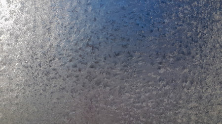 Frosty natural pattern on winter window glass as an abstract background