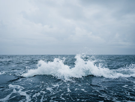 Sea wave with splashes of water on a background of blue sky