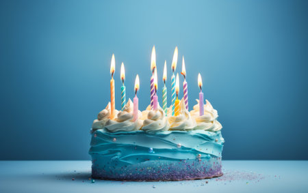 Birthday cake with burning candles on blue background, close-upの素材