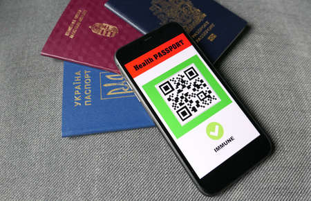 smartphone on gray background with digital health passport app with three passports for travel  immuneの写真素材