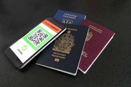 smartphone on black background with digital health passport app with three passports for travel ...