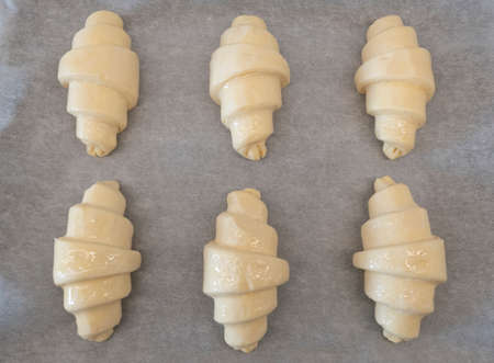 Croissant unbaked fresh on board with baking paper for homemade breakfastの写真素材