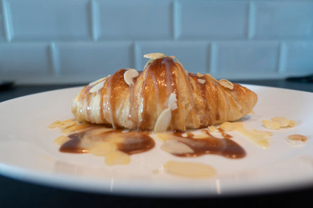 Baked Croissant with caramel and syrup on white plate for homemade breakfast with almondの写真素材