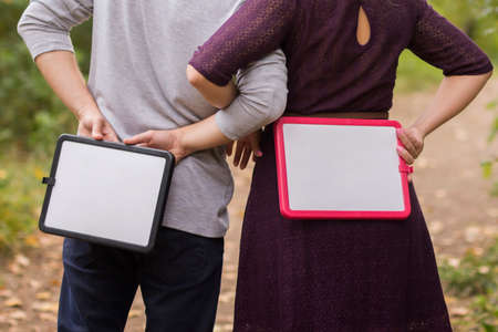 woman and man stand backwards and hold with platesの写真素材