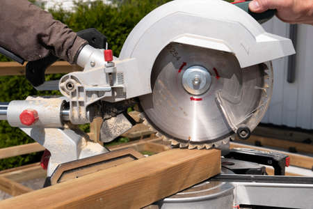 Building contractor worker using hand held worm drive circular saw to cut boards on a new home constructiion projectの写真素材
