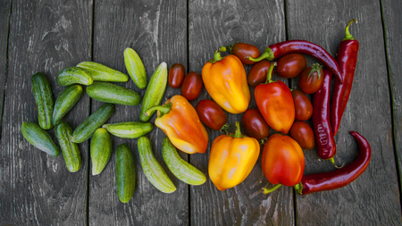 fresh vegetables, cucumbers, tomatoes, peppers, on a wooden tableの写真素材