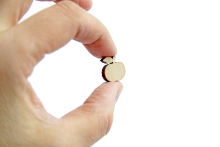 Small wooden apple in hand on isolated backgroundの写真素材