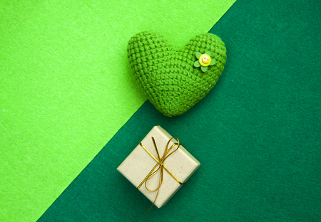 green knitted heart and gift box on a green background, a symbol of love to congratulate the holidayの写真素材