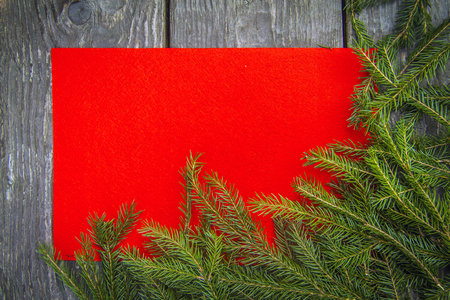 bright christmas background with a copy space with  fir branches with wooden table and a red textureの写真素材
