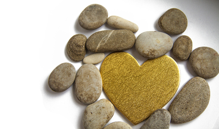 golden heart surrounded by stones on a white backgroundの写真素材