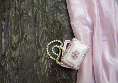 pink background with gift box and pearl beads and a roseの写真素材