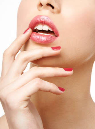 woman close up with pink glossy lipstick and red nail polishの写真素材