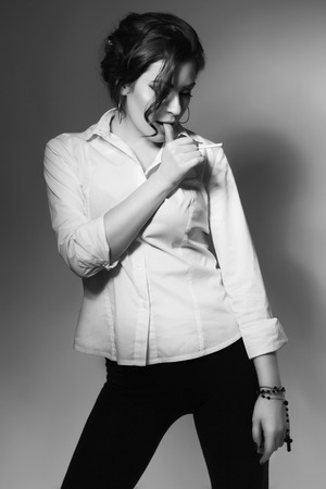 Young beautiful woman smoking cigarette, addicted. Bad habit. Messy hairstyle. Black and whiteの写真素材