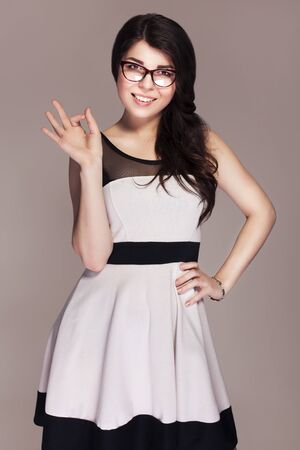 Beautiful brunette caucasian business woman in classic dress and glasses. neutral grey backgroundの写真素材