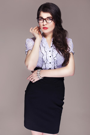 Beautiful brunette caucasian business woman in classic dress and glasses looks like teacher. neutral grey backgroundの写真素材