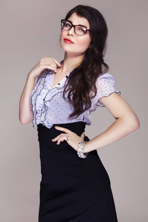 Beautiful brunette caucasian business woman in classic dress and glasses looks like teacher. neutral grey backgroundの写真素材