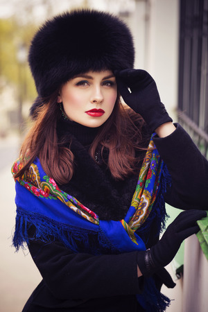 Beautiful brunette russian noblewoman outdoors on autumn day. red lips. black coat and a hat. Ornamental shawl. National traditional outfitの写真素材