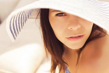 Beautiful brunette woman on the beach alone relaxing in a hat. Summer. Outdoors. Copy spaceの写真素材