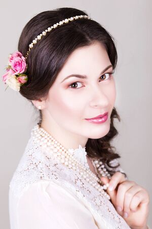 Beautiful brunette bride smiling with natural make up and flowers roses in her hairstyle and looking sidewaysの写真素材