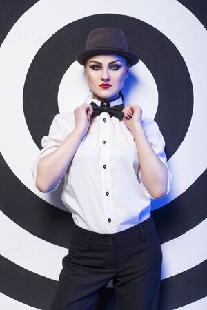 Pretty woman with evening make up and red lips in a bow-tie in a center of a dartboard backgroundの写真素材