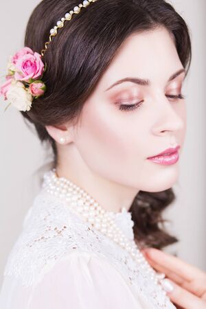 Beautiful brunette bride smiling with natural make up and flowers roses in her hairstyle and looking sidewaysの写真素材