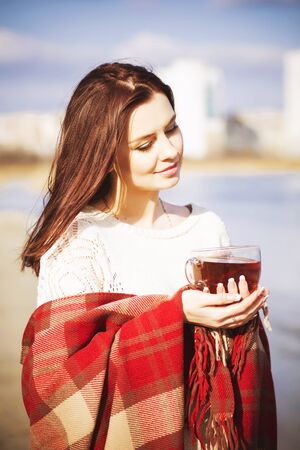 woman on a walk near river with tea and plaid blanketの写真素材