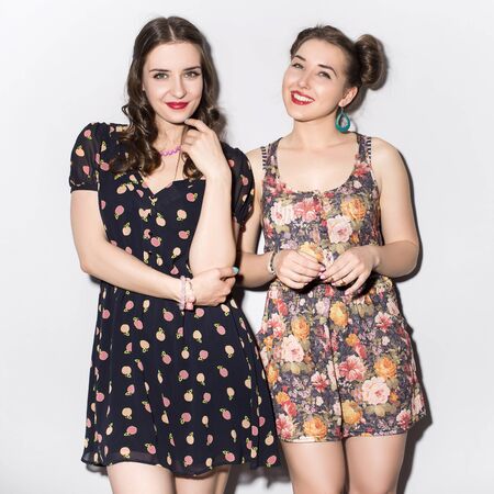 Two beautiful brunette women (girls) teenagers spend time together having fun, make funny faces. Casual hipsters outfit: romantic dressesの写真素材