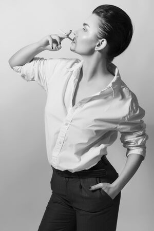 Androgyn transgender woman in men outfit: suit trousers and shirt and cigarette. indoors. black and whiteの写真素材