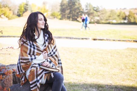 Beautiful caucasian brunette young woman in warm autumn day at park. Yellow leaves and sunshine....