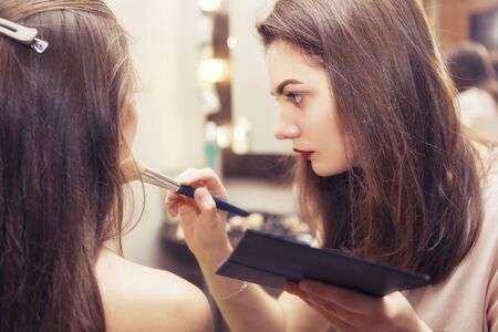 Brunette make up artist woman applying make up for a brunette bride in her wedding day