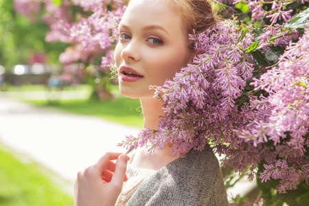 Beautiful red hair ginger slim young woman with fresh skin in casual outfit, posing with flowers....