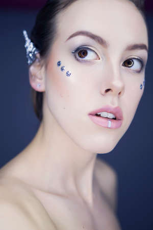 Beautiful futuristic style make up woman with foil ears and metallic accents on face. Neutral...