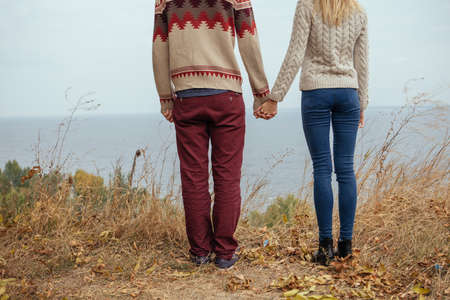 Happy thoughtful couple standing on a cliff near sea hugging each other in cold foggy cloudy autumn...