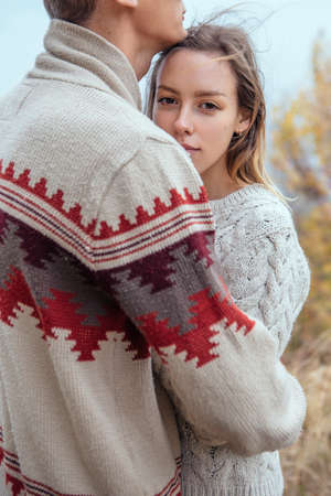 Happy thoughtful couple standing on a cliff near sea hugging each other in cold foggy cloudy autumn...