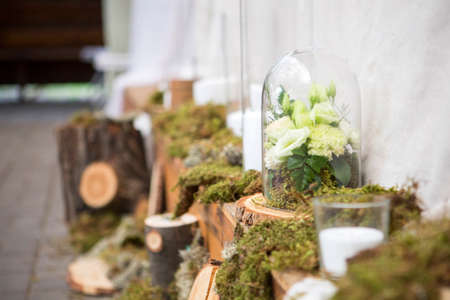 Fresh eustoma roses bouquet composition on a table in a glass vase. Wedding bridal decor. Dim dark sunset light. Romantic moodの写真素材