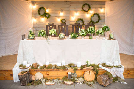 Fresh eustoma roses bouquet composition on a table in a glass vase. Wedding bridal decor. Dim dark sunset light. Romantic moodの写真素材