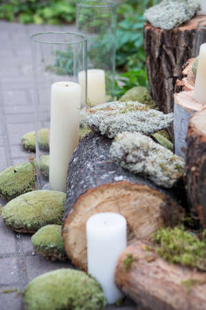 Stumps decorated with moss and candles in garden, on a wedding ceremony. Soft day light, outdoorの写真素材