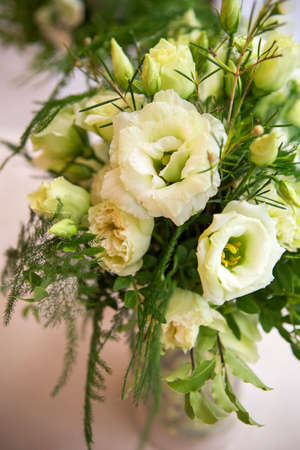 Fresh eustoma roses bouquet composition on a table in a glass vase. Wedding bridal decor. Dim dark sunset light. Romantic moodの写真素材